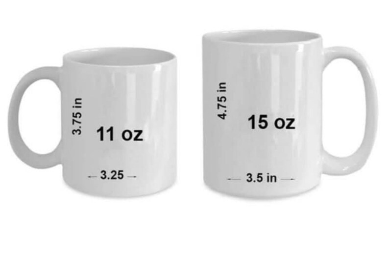 May include: Two white ceramic mugs with black text. The smaller mug is 11 oz and 3.75 inches tall. The larger mug is 15 oz and 4.75 inches tall.