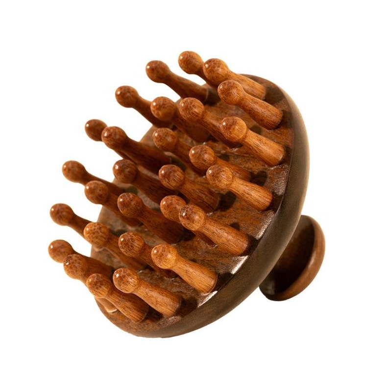 K&ouml;nnte beinhalten: Ein Holz-Kopfhaut-Massageger&auml;t mit einer dunkelbraunen Basis und einem runden Kopf mit zahlreichen Holzborsten. Die Borsten sind kreisf&ouml;rmig angeordnet und alle gleich gro&szlig; und geformt.