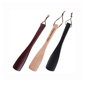 May include: Three shoe horns in varying colors: dark brown, natural wood, and black. Each horn has a leather loop for hanging and the text "Engrave Logo" is printed on the natural wood horn.