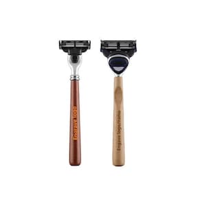 Puede incluir: Dos maquinillas de afeitar con mango de madera y cabezales negros y plateados. Los mangos están grabados con "Engrave logo" y "Engrave logo/name".