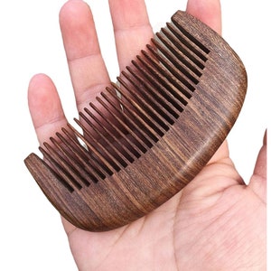 May include: A dark brown wooden comb with a curved handle and fine teeth. The comb is made of a dark wood with a natural grain pattern.