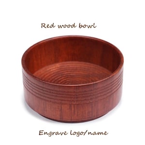 Op de afbeelding: Een rode houten kom met een gladde, ronde binnenkant en een gegroefde buitenkant. De kom is perfect voor het bewaren van kleine voorwerpen of het serveren van snacks.