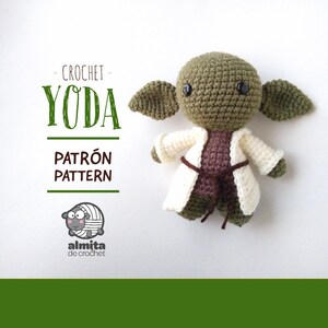Puede incluir: Muñeco amigurumi de Yoda tejido a crochet con una túnica blanca y un cinturón marrón. El muñeco tiene la piel verde, orejas grandes y ojos negros. La imagen incluye el texto "CROCHET - YODA - PATRÓN PATTERN - almita de crochet".
