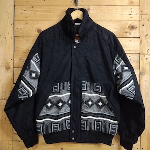 May include: A black quilted jacket with a geometric pattern on the sleeves and bottom. The pattern is in shades of white and gray.