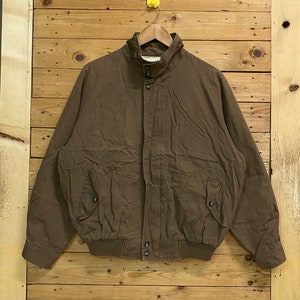May include: A brown bomber jacket with a high collar, zip fastening, and elasticated waistband.