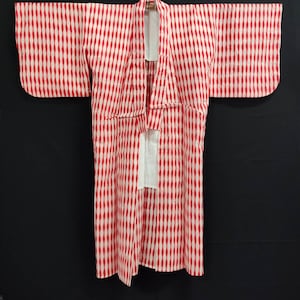 Puede incluir: Un kimono japonés de patrón rojo y blanco con una faja blanca. El kimono está hecho de una tela ligera y tiene un diseño tradicional.