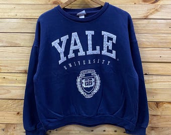 May include: Navy blue Yale University sweatshirt with white lettering and a crest. The sweatshirt features the word "YALE" in large, block letters across the chest, with "UNIVERSITY" below. A crest is centered below the text.