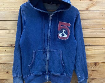 May include: Blue zip-up hoodie with a hood and front pockets. The hoodie features a red patch with the number 5 and a cartoon dog graphic. The garment has a faded, worn appearance.