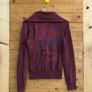 Peut inclure: Une veste zippée bordeaux avec un imprimé floral et un col et des poignets côtelés.
