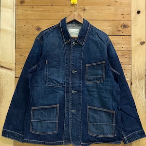 May include: A dark blue denim jacket with a button-up front, two chest pockets, and two large flap pockets. The jacket has a collar and long sleeves.