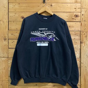 May include: Black sweatshirt with a purple and white graphic of a flying bird with the text "PROPERTY OF NORTH FORSYTH RAIDERS PHYS. ED. DEPT."