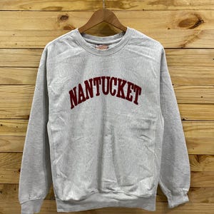 Puede incluir: Una sudadera gris con la palabra "NANTUCKET" bordada en rojo en la parte delantera.