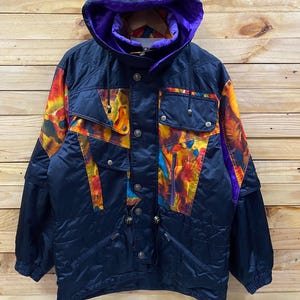 May include: A vintage black ski jacket with a vibrant abstract pattern in orange, yellow, and blue. The jacket features a hood with a purple lining, multiple pockets, and a zip closure. Designed for cold weather, it's a retro ski jacket.