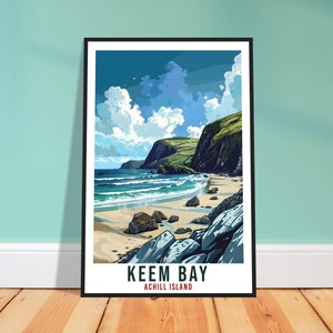 May include: A poster with a scenic view of Keem Bay on Achill Island, Ireland. The poster features a blue sky with white clouds, a sandy beach, and a rocky coastline. The text "Keem Bay" and "Achill Island" is printed in black at the bottom of the poster.