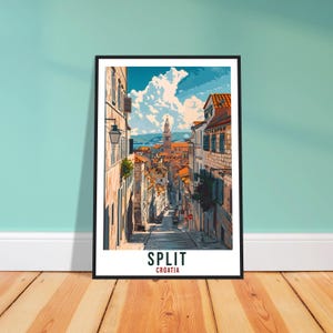 May include: A framed art print depicting a street scene in Split, Croatia, with buildings, a church tower, and a cloudy sky. The print has a white border and the words "SPLIT" and "CROATIA" at the bottom.