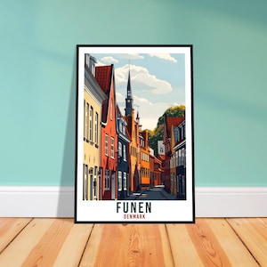Könnte beinhalten: Ein gerahmter Kunstdruck, der eine farbenfrohe Straßenszene in Fünen, Dänemark, zeigt. Das Kunstwerk zeigt Gebäude mit roten, gelben und orangen Fassaden, einen hohen Kirchturm und den Text "FUNEN DENMARK" unten.