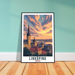 May include: A framed art print of Linköping, Sweden, featuring a detailed cityscape under a vibrant sunset sky. The artwork showcases buildings with red roofs, a tall church tower, and the text "LINKÖPING SWEDEN" at the bottom.