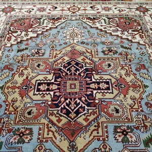 May include: A traditional Persian rug with a blue, red, and cream color scheme. The rug features a central medallion with intricate geometric patterns and floral motifs.