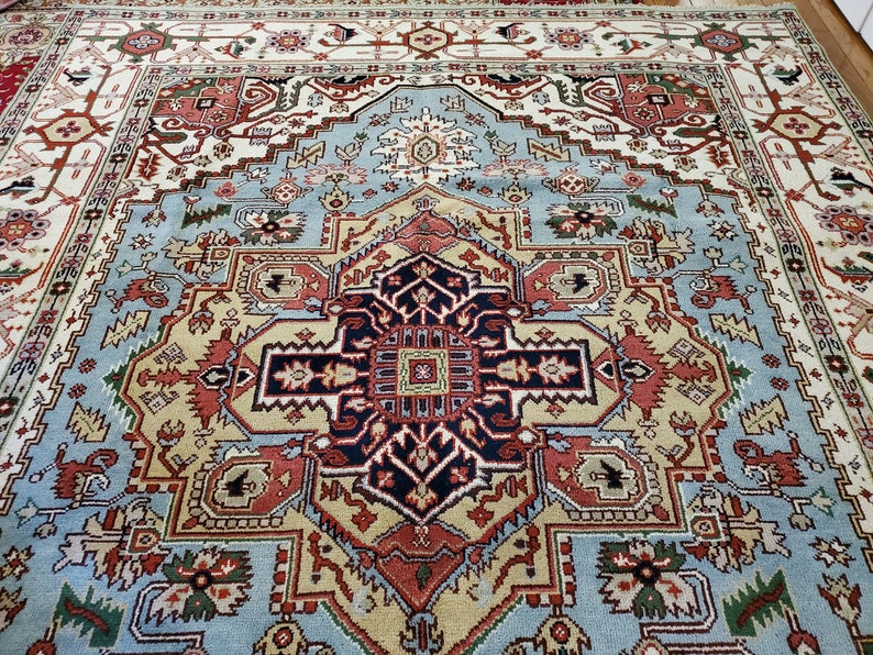 May include: A traditional Persian rug with a blue, red, and cream color scheme. The rug features a central medallion with intricate geometric patterns and floral motifs.