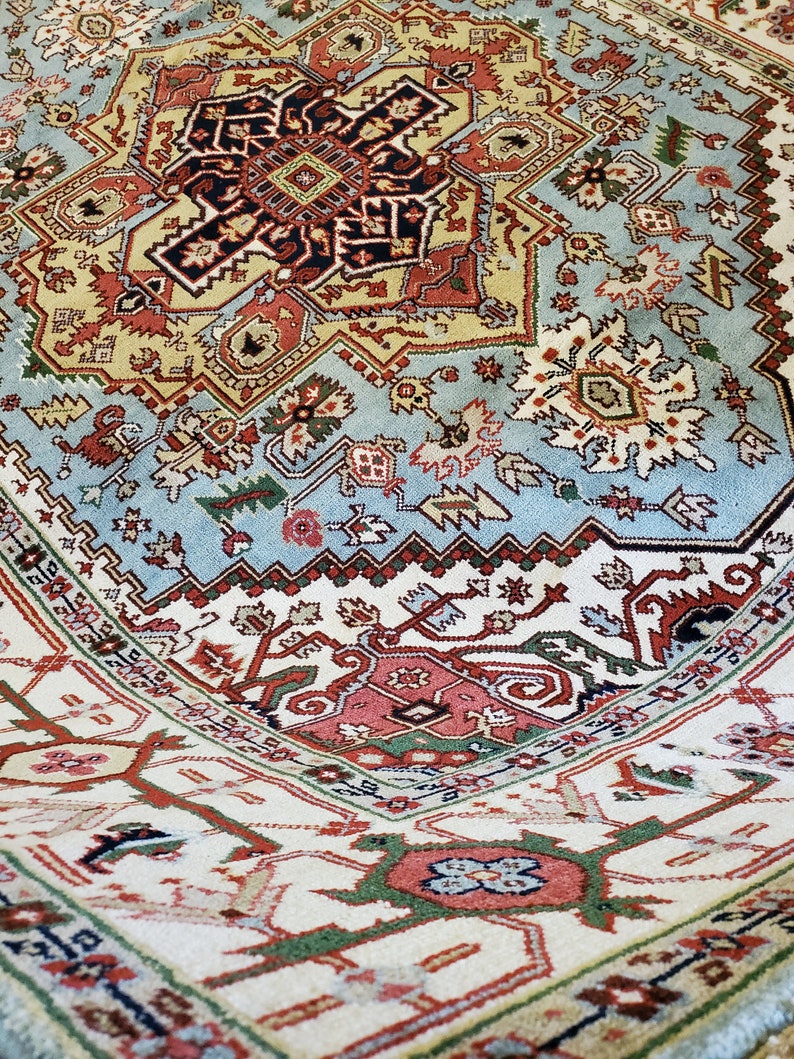 May include: A detailed, colorful rug with a central medallion and intricate geometric patterns. The rug features shades of blue, red, green, and white.