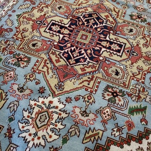 May include: A blue, beige, red, and black patterned rug with intricate designs. The rug has a central medallion with a geometric pattern.