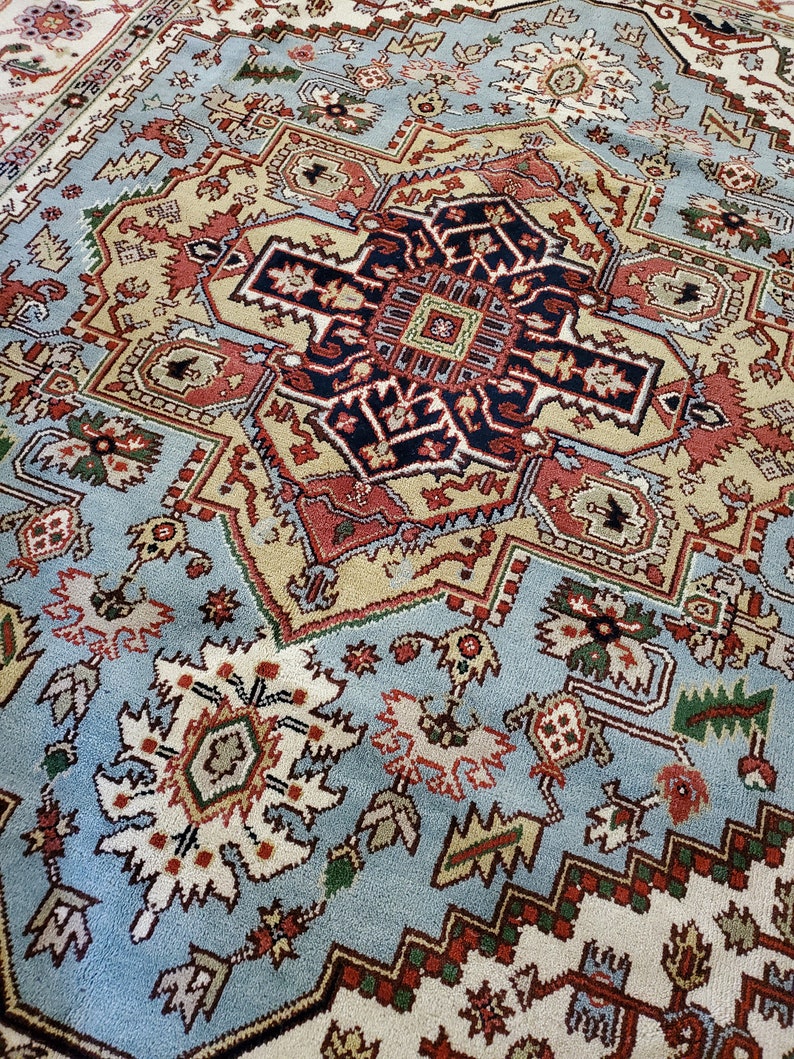 May include: A blue, beige, red, and black patterned rug with intricate designs. The rug has a central medallion with a geometric pattern.