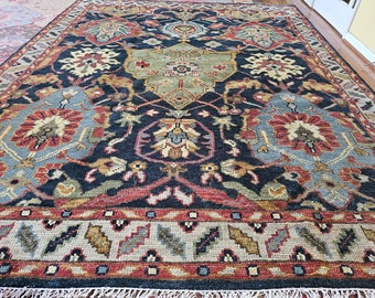 Può includere: Un tappeto blu scuro con un design persiano tradizionale. Il tappeto presenta intricati motivi floreali in tonalità di rosso, beige e blu.