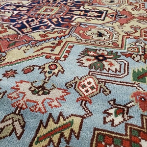 May include: A close-up of a blue, red, green, and white patterned rug with intricate designs. The rug has a soft, plush texture.