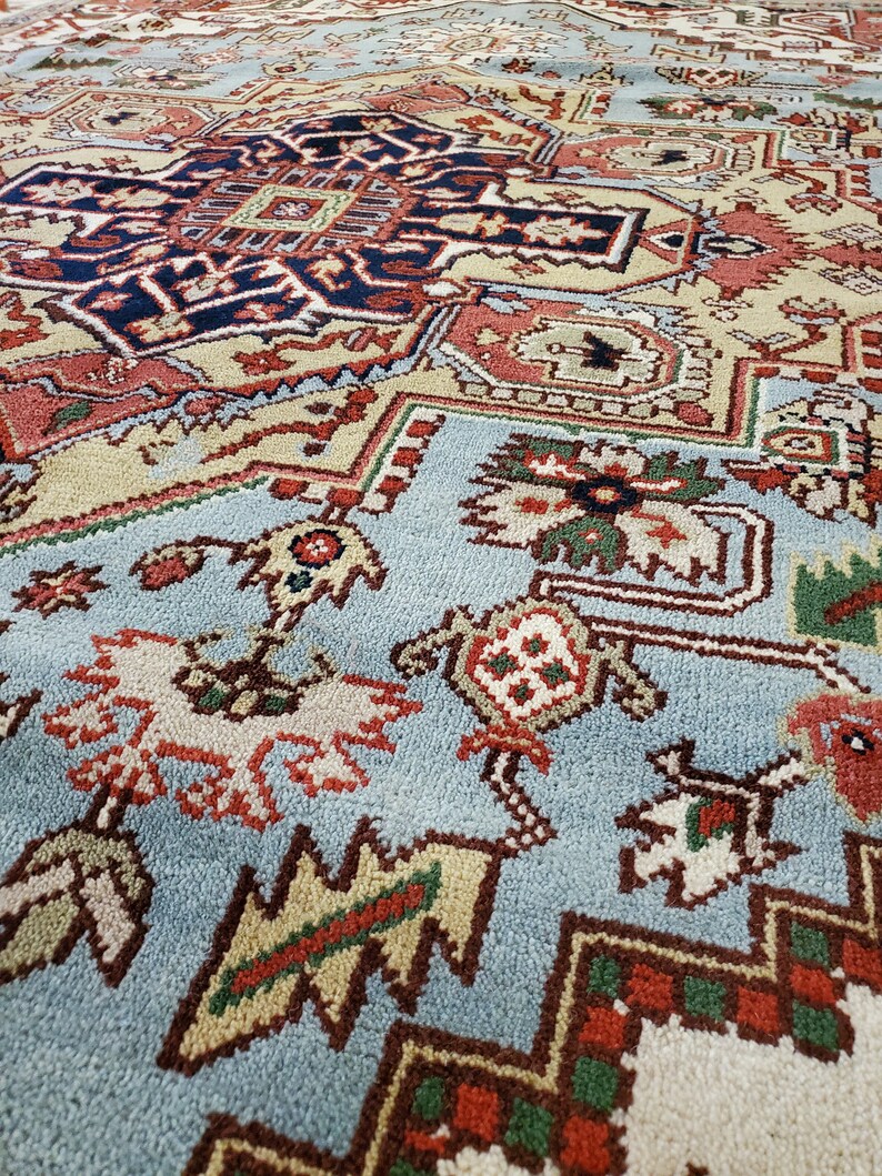 May include: A close-up of a blue, red, green, and white patterned rug with intricate designs. The rug has a soft, plush texture.