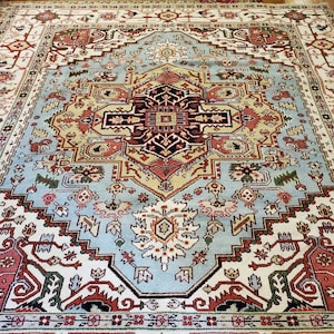 May include: A traditional Persian rug with a blue, red, and cream color scheme. The rug features a central medallion with intricate floral and geometric patterns.