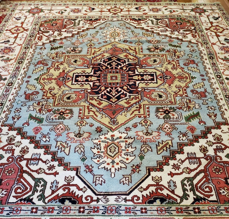 May include: A traditional Persian rug with a blue, red, and cream color scheme. The rug features a central medallion with intricate floral and geometric patterns.