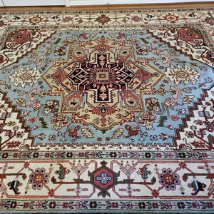 May include: A large, intricately patterned rug with a central medallion in shades of blue, red, and cream. The rug has a traditional Persian design with floral and geometric motifs.