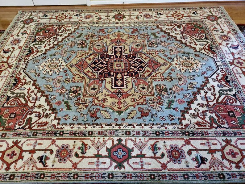May include: A large, intricately patterned rug with a central medallion in shades of blue, red, and cream. The rug has a traditional Persian design with floral and geometric motifs.