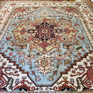 May include: A large, intricately patterned rug with a central medallion in shades of blue, red, and cream. The rug has a traditional Persian design with floral motifs and geometric shapes.