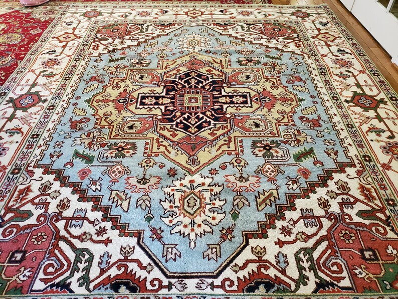 May include: A large, intricately patterned rug with a central medallion in shades of blue, red, and cream. The rug has a traditional Persian design with floral motifs and geometric shapes.