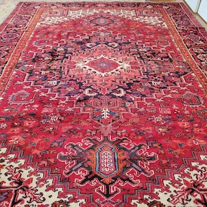 May include: A red, blue, and white Persian rug with a geometric pattern. The rug has a central medallion and a border with intricate details.