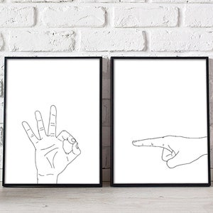 May include: Two framed art prints. One print features a hand making the "OK" gesture with fingers. The other print shows a hand pointing to the right. Both prints have a white background and black line art.