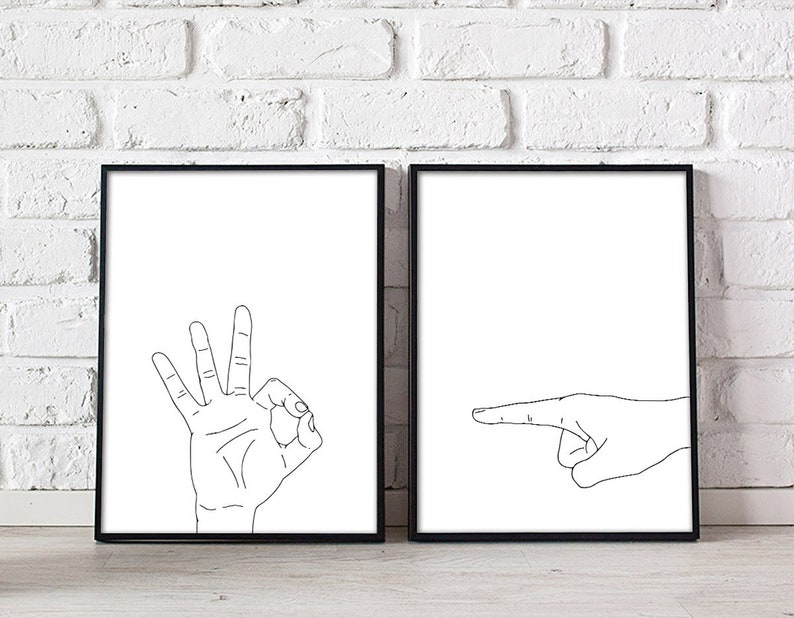 May include: Two framed art prints. One print features a hand making the "OK" gesture with fingers. The other print shows a hand pointing to the right. Both prints have a white background and black line art.
