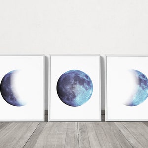 May include: Three framed prints of a blue moon in different phases. The moon is a watercolor style with a blue and white color scheme.