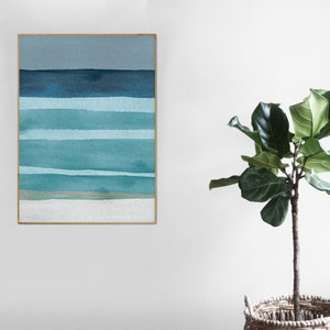 May include: A framed abstract watercolor painting with horizontal stripes in shades of blue and green. The painting is on a white wall with a potted plant in the foreground.
