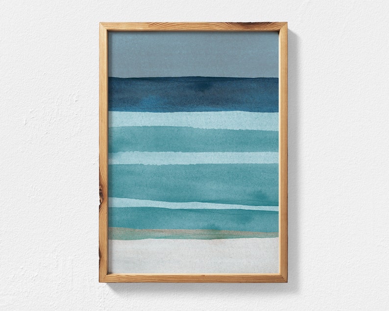 May include: A framed abstract watercolor painting with horizontal stripes in shades of blue and green. The painting depicts a seascape with a light blue sky and a sandy beach.