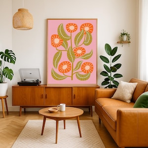 May include: A framed floral art print featuring orange flowers and olive green leaves against a pink background. The artwork is displayed above a wooden cabinet in a living room setting. A turntable and a leather sofa are also visible.