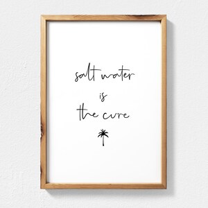 Puede incluir: Una impresión enmarcada con el texto "salt water is the cure" y un pequeño icono de palmera debajo del texto.