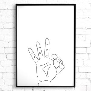 May include: Black framed art print featuring a hand gesture. The hand is depicted in a line drawing, with the thumb and index finger forming a circle, and the other three fingers extended upwards. The background is white.