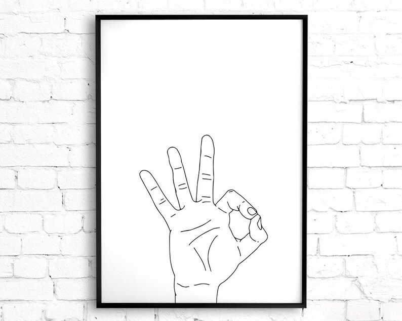 May include: Black framed art print featuring a hand gesture. The hand is depicted in a line drawing, with the thumb and index finger forming a circle, and the other three fingers extended upwards. The background is white.