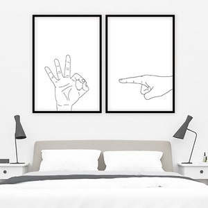 May include: Two framed minimalist art prints. One print features a hand making the "OK" gesture, and the other shows a hand pointing to the right. Both prints have a white background with black line drawings.