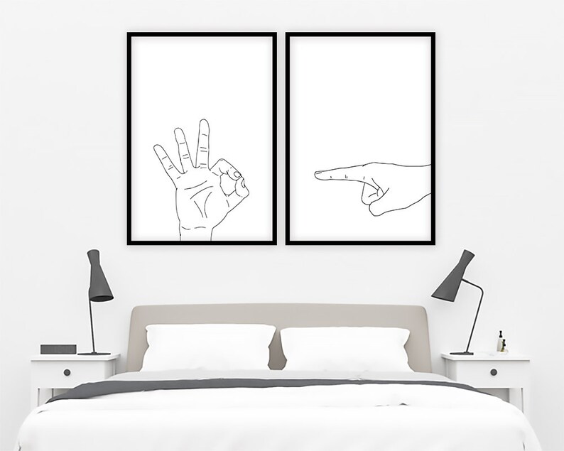 May include: Two framed minimalist art prints. One print features a hand making the "OK" gesture, and the other shows a hand pointing to the right. Both prints have a white background with black line drawings.