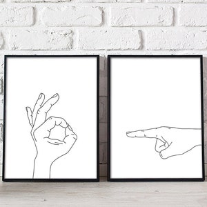 Puede incluir: Dos impresiones enmarcadas en negro con fondos blancos. La impresi&oacute;n de la izquierda muestra un dibujo lineal de una mano haciendo el signo de OK. La impresi&oacute;n de la derecha muestra un dibujo lineal de una mano apuntando hacia la derecha.