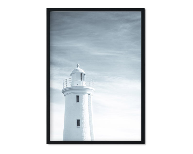 Pu&ograve; includere: Un faro bianco con una ringhiera nera si erge alto contro un cielo nuvoloso e blu. Il faro &egrave; un design architettonico classico con una cima arrotondata e una serie di finestre.