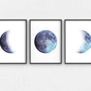 May include: Three framed prints of the moon in different phases. The moon is a blue and white color. The frames are black.